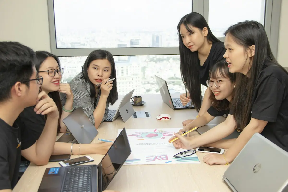 Nhóm bạn trẻ ngồi cùng nhau với máy tính xách tay để học nhóm